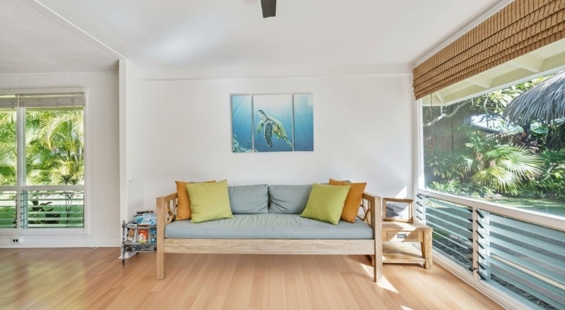 Timber flooring displayed in a bright living room with natural light, wooden furniture, and a relaxed coastal-style interior.